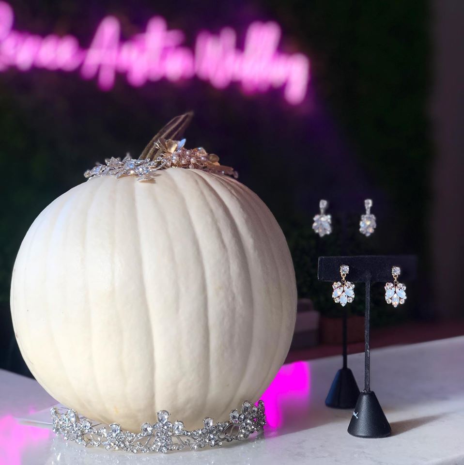 White pumpkin sitting over a tiara and some silver drop earrings next to the pumpkin and some hairpieces on top of the pumpkin