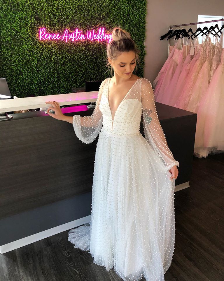 Model wearing a white long sleeve wedding gown